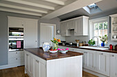 White fitted kitchen with cut flowers in Surrey home, England, UK
