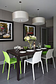 Lime green and white dining chairs at table with artwork in contemporary London home, England, UK