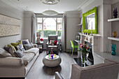 Lime green mirror frame above fireplace with lilies and marble coffee table in contemporary London home, England, UK