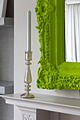 Silver candlestick with lime green decorative mirror frame in living room detail of contemporary London home, England, UK