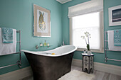 Freestanding back with orchid and artwork at window of London bathroom, England, UK