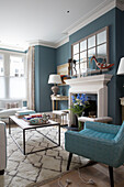 Retro styled blue armchair and table in living room of London home, England, UK
