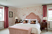 Pink headboard and wallpaper with matching bedside lamps in Pewsey country house Wiltshire England UK