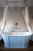 Light blue freestanding bath with white shower curtains in Wokingham cottage Berkshire UK