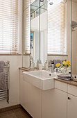 Large mirror above washbasin at window in London townhouse UK
