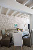 Slip-covered dining chairs at table with beamed ceiling in 18th century Ithaca townhouse Greece