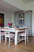 Dining table and chairs with kitchen dresser in Sussex country house England UK