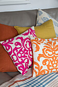 Pink and orange cushions on sofa in Surrey living room England UK