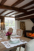 Lit fire and candles with place setting on wooden dining table in Surrey home England UK