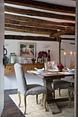 Light grey dining chair at candlelit table in beamed Surrey home England UK