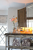 Lit candle with cut flowers on vintage dresser in Surrey cottage England UK
