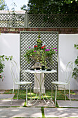 Wrought iron metal chairs and table in walled garden with trellis Dorset England UK