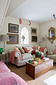 Arched window above sofa with wooden blanket box in Dorset living room England UK