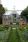 Greenhouse with weathervane and rusty benches in Arundel garden West Sussex England UK
