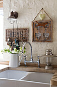 Key rack and artwork with vintage lamps beside double sink in renovated Victorian schoolhouse West Sussex England UK