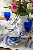 Cut flowers at place setting with blue glassware on table in London townhouse UK