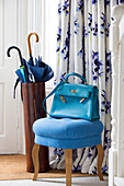 Turquoise handbag on stool with umbrella stand at front door of London townhouse UK