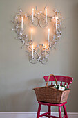 Lit candles in wall-mounted heart with basket on pink chair in UK home