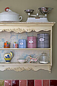 Striped storage tins on wall-mounted kitchen shelves in UK home