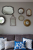 Vintage mirror collection above sofa with blue and white cushions UK home