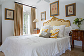 Gilt headboard on double bed at French windows in Var farmhouse Provence France