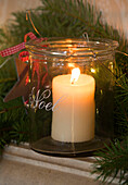 Beleuchtete Kerze in einem Vorratsglas zu Weihnachten in einem Haus in Sussex, England UK