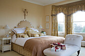 Gift wrapped presents on chaise longue at foot of double bed in Sussex home England UK