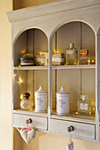 Perfume bottles and toiletries on wall-mounted shelving in Sussex bathroom England UK