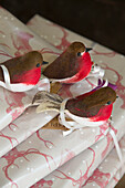 Three Christmas robins on gift wrapped presents in Surrey home England UK