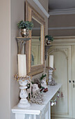 Large candles and Christmas decorations on mantlepiece with mirror in London bedroom England UK