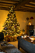 Mit Lichterketten beleuchteter Weihnachtsbaum unter einer Balkendecke in einem Haus in Kent England UK