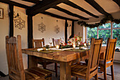 Solid wooden chairs at table in beamed dining room of Kent home England UK