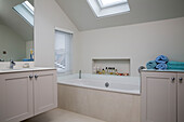 Marble bath below skylight window in modernised Victorian cottage Sussex England UK