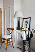 Wooden chair and umbrella stand in hallway of London townhouse apartment UK