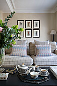 Teaset on coffee table with sofa and framed prints in London townhouse apartment UK
