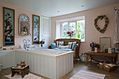 Wicker sofa below window with panelled bath in 19th century Somerset cottage England UK