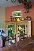 Wooden cupboard with fruit mural in kitchen of 19th century Somerset cottage England UK
