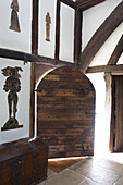 Arched wooden door with figures and wooden chest in timber framed Kent farmhouse UK