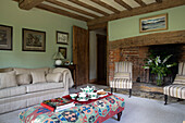 Striped chairs at fireplace with tea set on ottoman in light green living room Kent UK