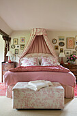 Pink gingham with toile de jouy blanket box at foot of bed with canopy in Kent farmhouse UK