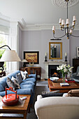Lilies on wooden coffee table with blue sofa in living room of London townhouse UK
