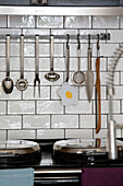 Utensilienhalter über schwarzem Herd in gekachelter Küche eines Londoner Stadthauses UK