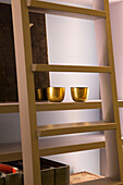 Gold candle holders on bookshelf with ladder in London townhouse UK