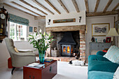 Armchair and sofa at lit fireside in Grade II listed cottage Hampshire England UK