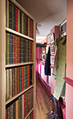 Hardbacked books on shelving in hallway entrance of Grade II listed cottage in Hampshire England UK