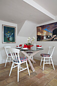 White painted dining chairs at glass topped table in Victorian terraced house London England UK