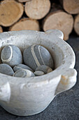 Pebbles in bowl with firewood in Sussex beach house England UK