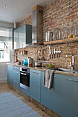 Fitted teal units in exposed brick kitchen of Sussex beach house England UK
