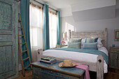 Light blue and net curtains at sunlit window of double bedroom in Sussex beach house England UK
