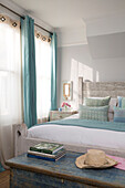 Light blue and net curtains at sunlit window of double bedroom in Sussex beach house England UK